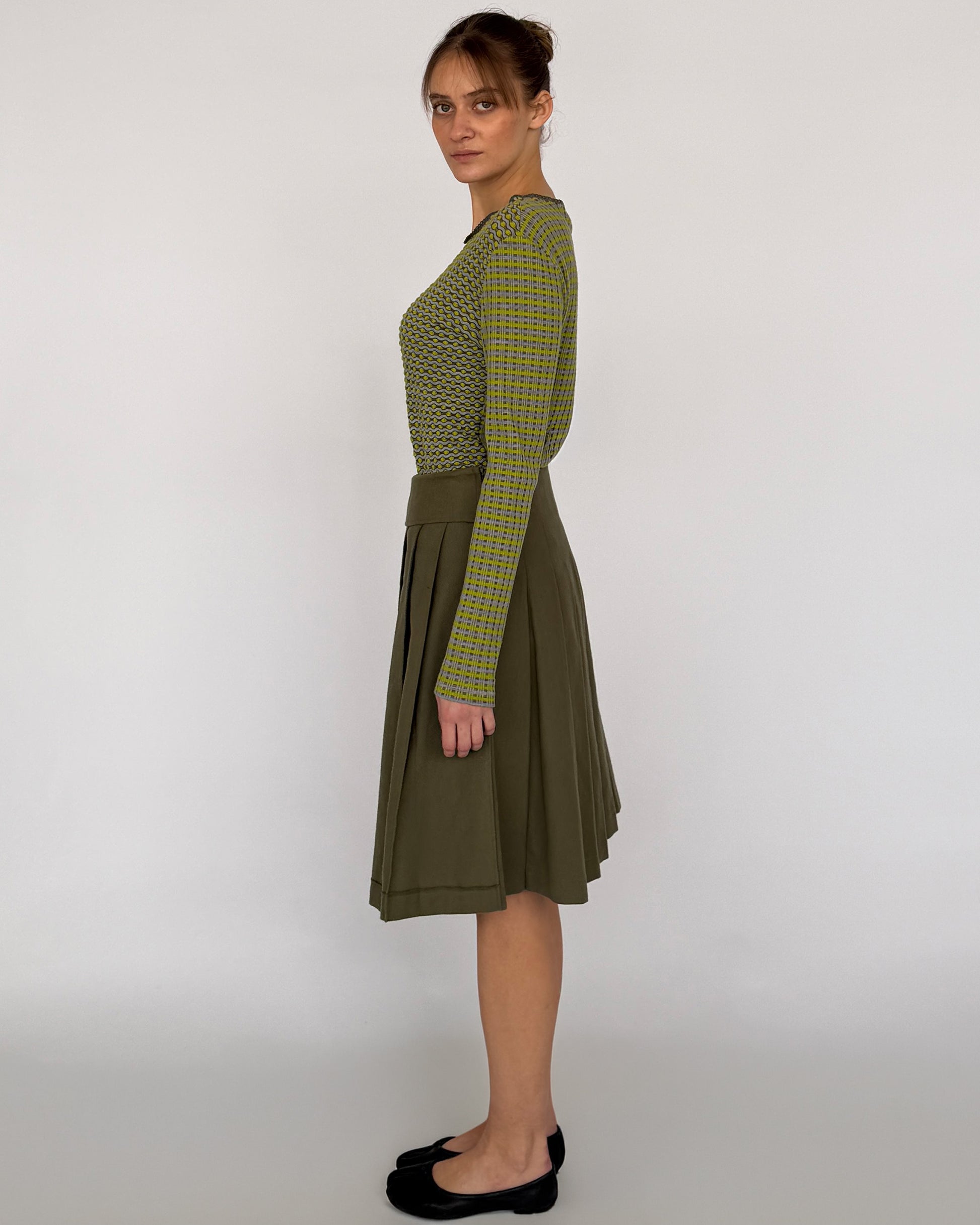 Side view of Comme des Garçon green pleated midi skirt