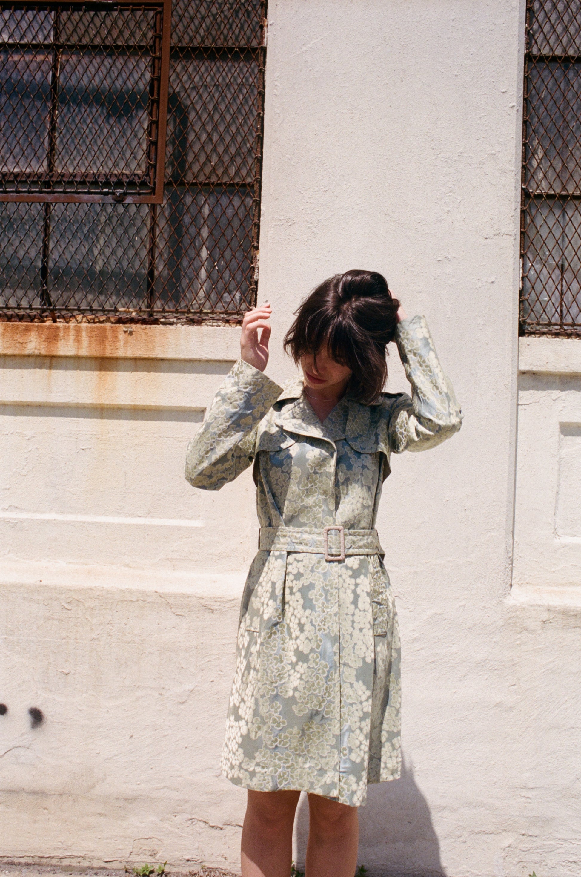 Woman in a floral moschino jacket standing against a textured wall.