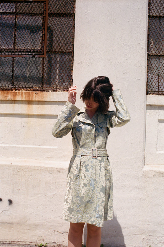 Woman in a floral moschino jacket standing against a textured wall.