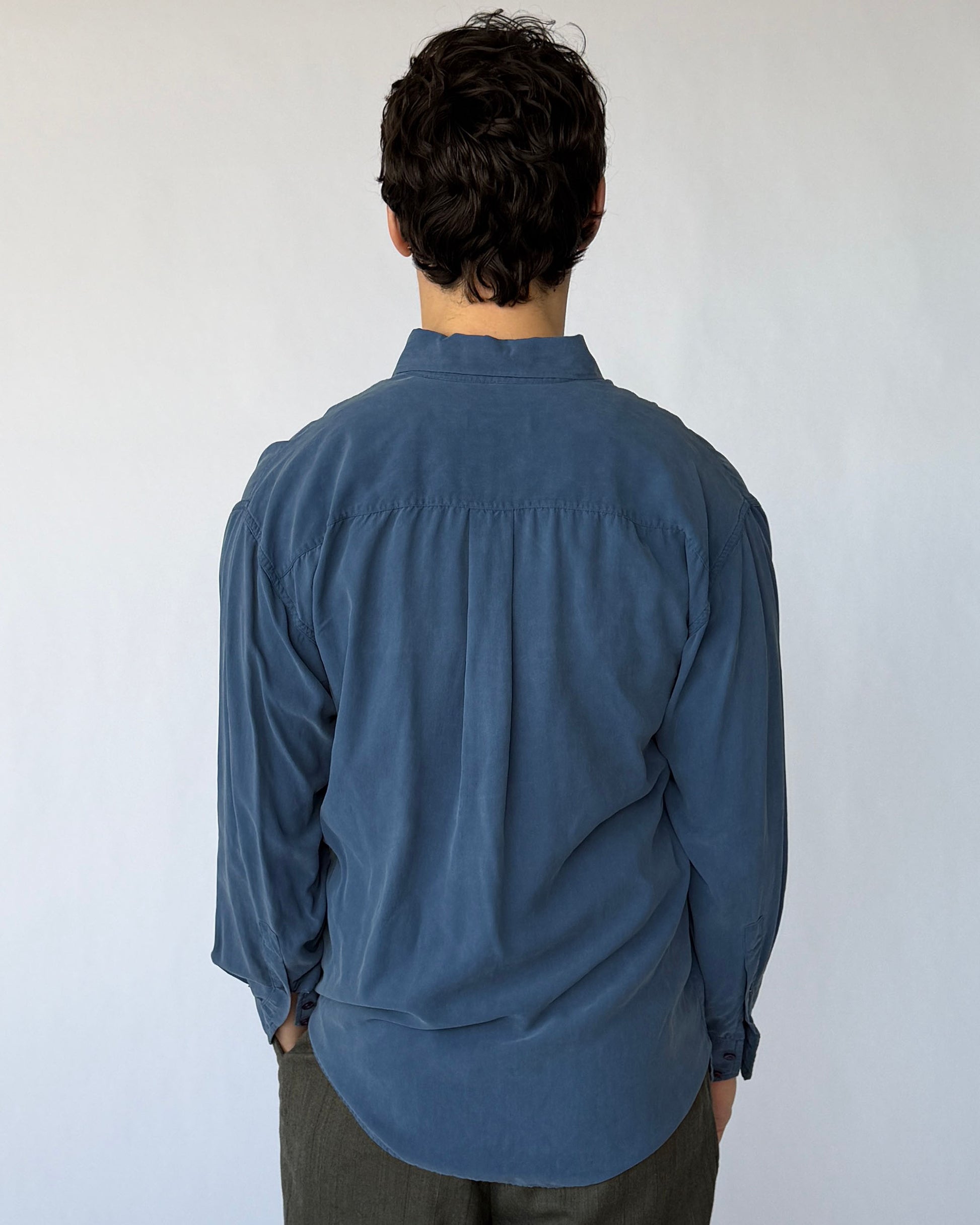 Back view of vintage blue silk button-up shirt with relaxed drape and curved hem